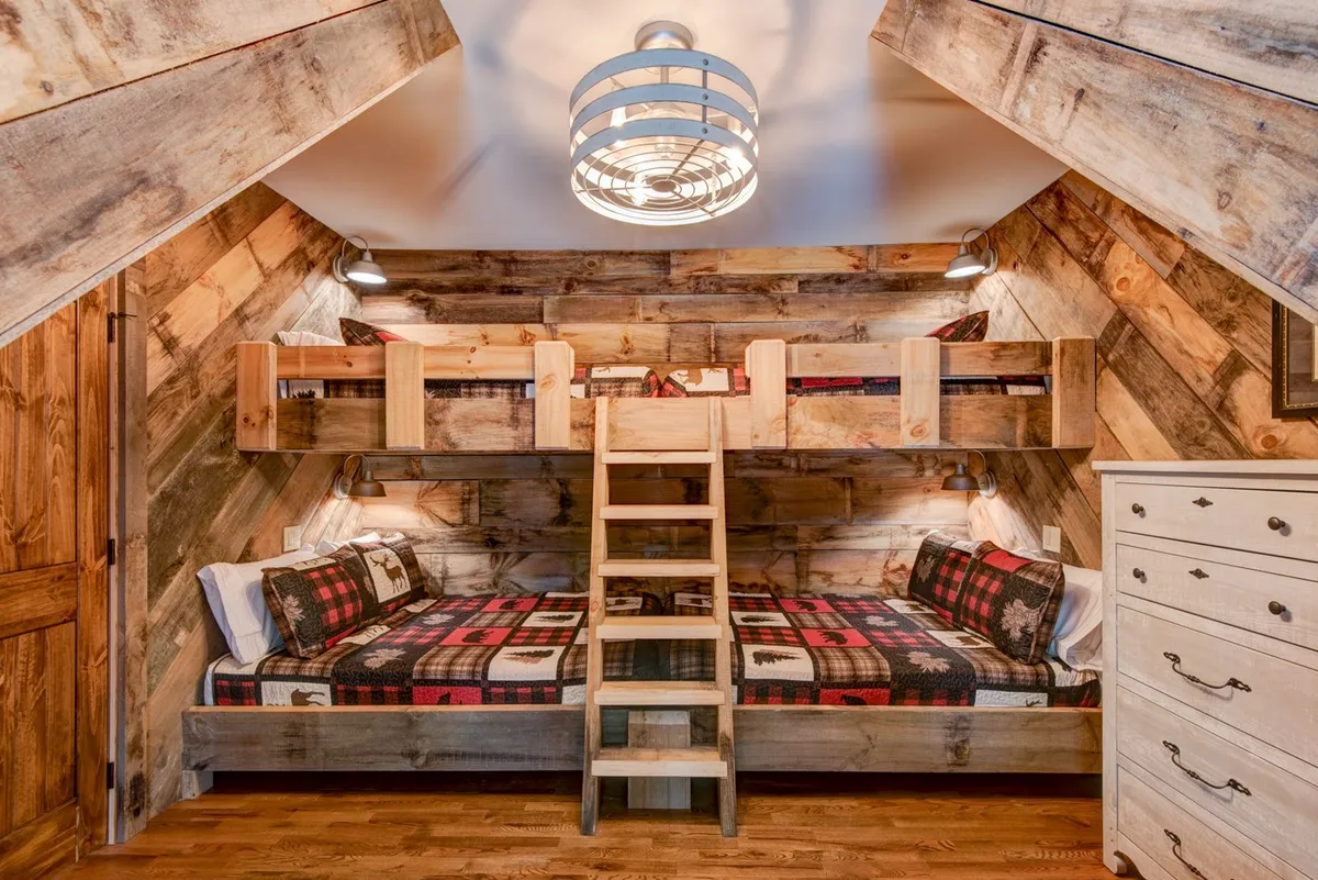 A whimsical bunk room with plaid blankets, wooden textures, and a unique light fixture. Designed for comfort and creativity, it features built-in bunk beds that invite play, storytelling, and late-night bonding.