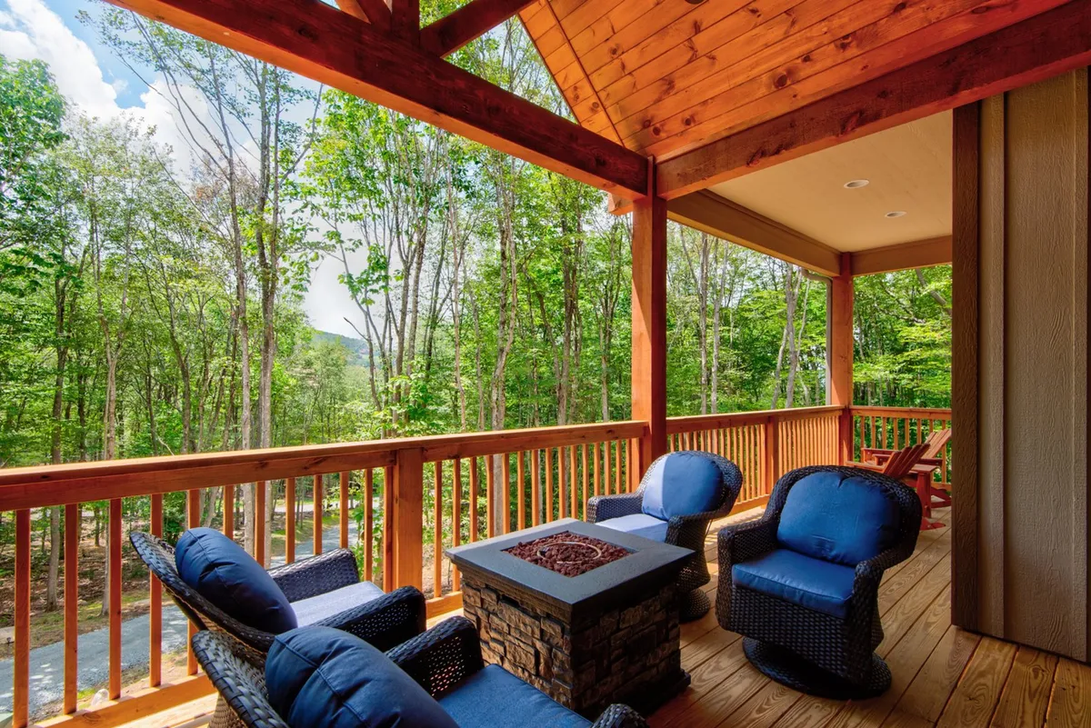 A cozy outdoor fire pit area with comfortable seating encircled by a wooden railing, set against a mountain backdrop. The setup is ideal for evening gatherings, storytelling, or stargazing.