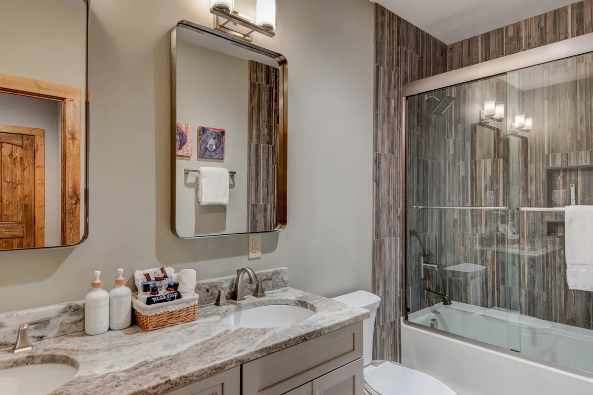 A spa-inspired bathroom with a double vanity, two mirrors, and a glimpse of a luxurious shower area. The color palette and finishes create an inviting, soothing ambiance ideal for relaxation and self-care.